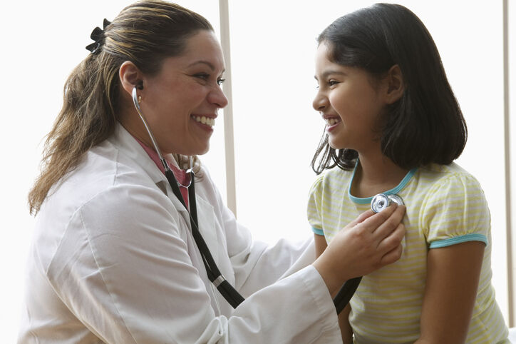 Female doctor listening to girl's heart with stethoscope